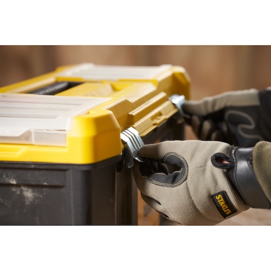 STANLEY STST75787-1 toolbox close-up with gloved hands securing metal latches, photography product.