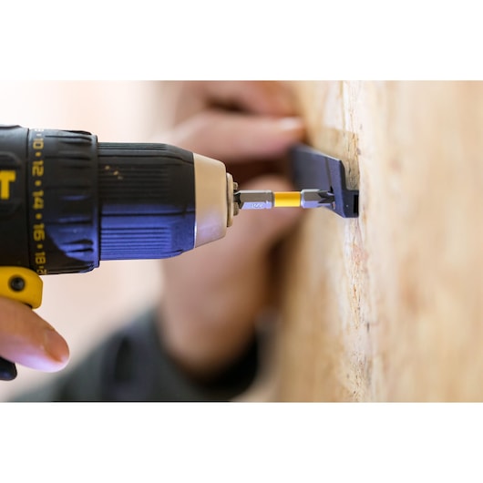 STANLEY STST82733-1 drill driving screw into wall bracket, close-up photography.