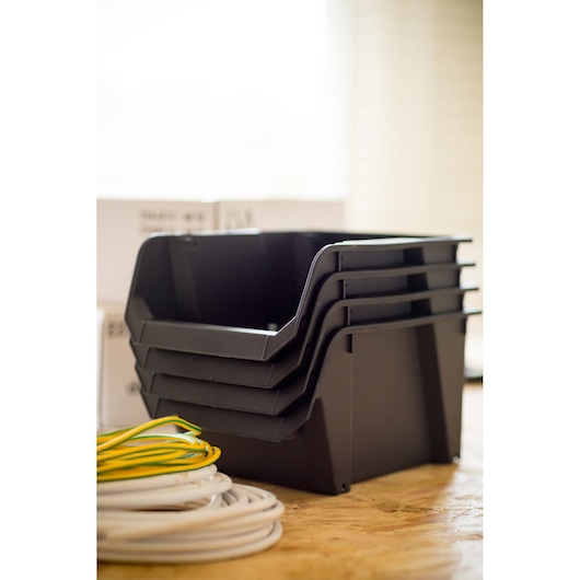STANLEY STST82734-1 stackable black storage bins shown side angle on workbench with electrical wires.