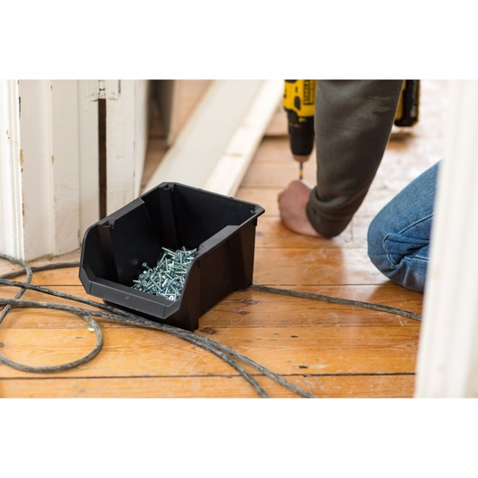 STANLEY STST82734-1 black storage bin with screws on floor during installation work.
