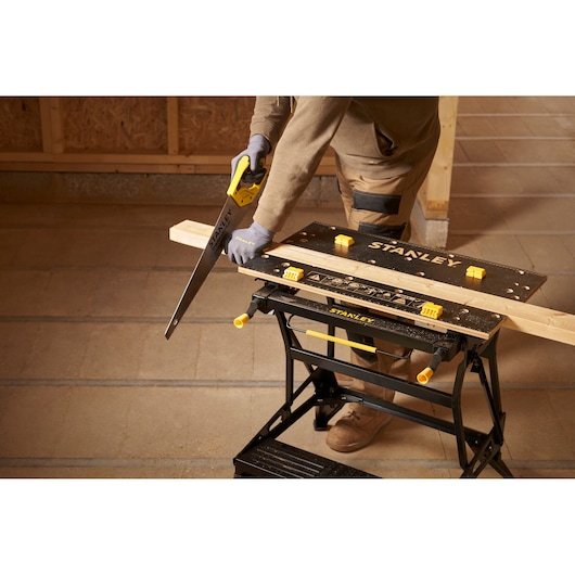 Photo of STANLEY STST83800-1 workbench used for woodworking, black tabletop with yellow clamps, workshop setting.