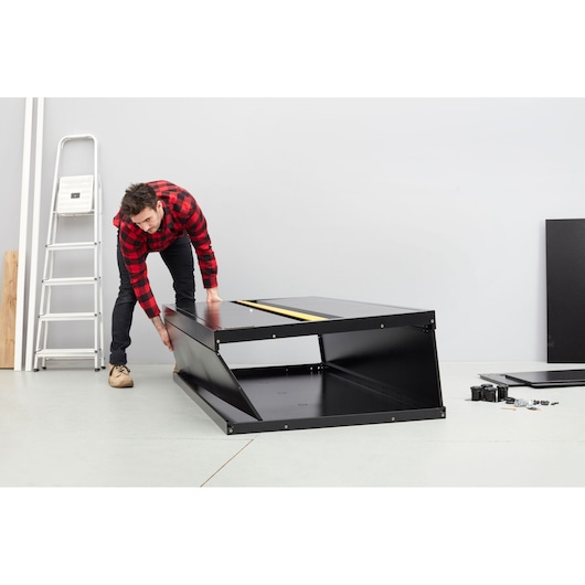 STANLEY STST97957-1 black cabinet being assembled, photo shows parts and tools on floor in workshop.